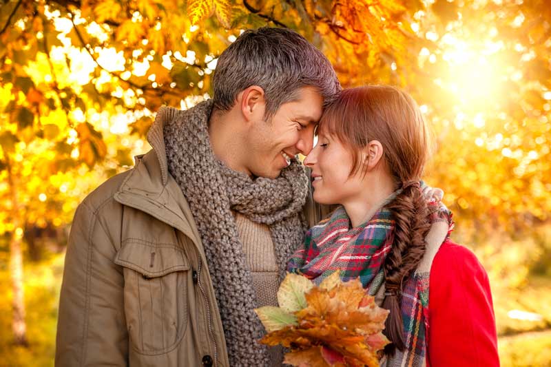 Stressfrei durch den Herbst: Ein Pärchen hält Blätter in der Hand, während die Sonne auf sie scheint