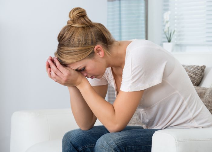 Frau leider unter Chronischem Fatigue-Syndrom und sitzt energielos auf der Couch