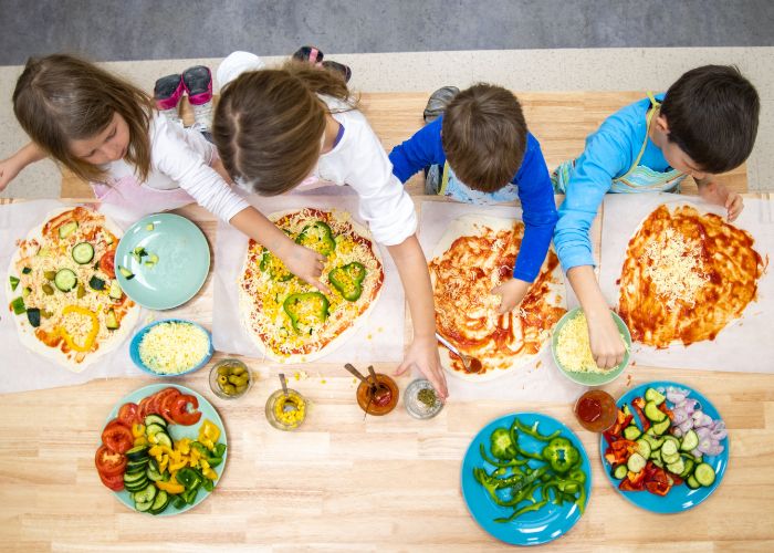 Kinder belegen Pizza mit Gemüse