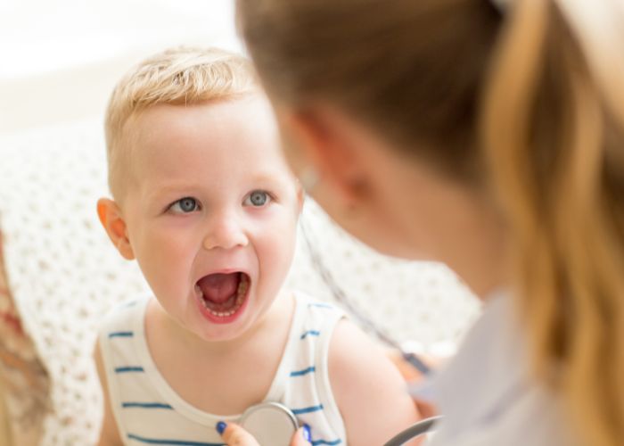 Kind zeigt seine Mundhöhle einer Ärztin