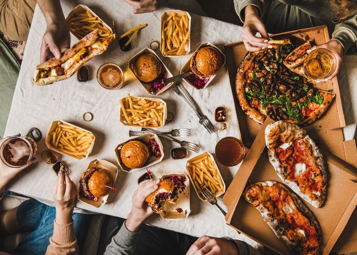 Fast Food wird von einer Gruppe von Freunden gemeinsam genossen - Western Diet als Ursache von Diabetes, Metabolischem Syndrom und Co