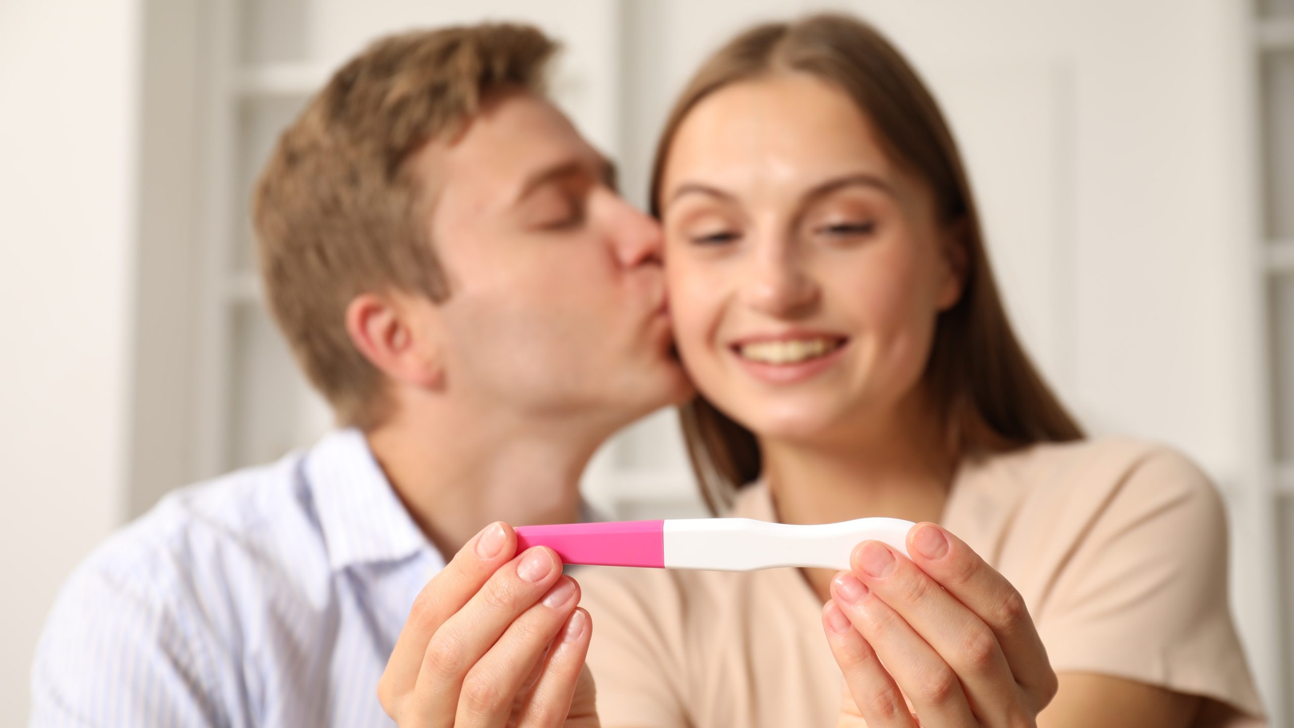 Kinderwunsch - glückliches Paar mit Schwangerschaftstest