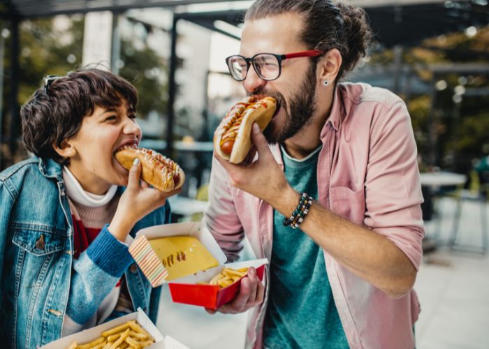 Fast Food: täglich am Tisch - Vater isst Hot Dog mit seinem Kind