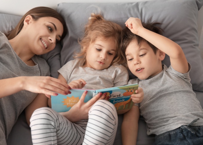 Una madre leyendo un libro a sus dos hijos, fomentando la relajación y el bienestar.